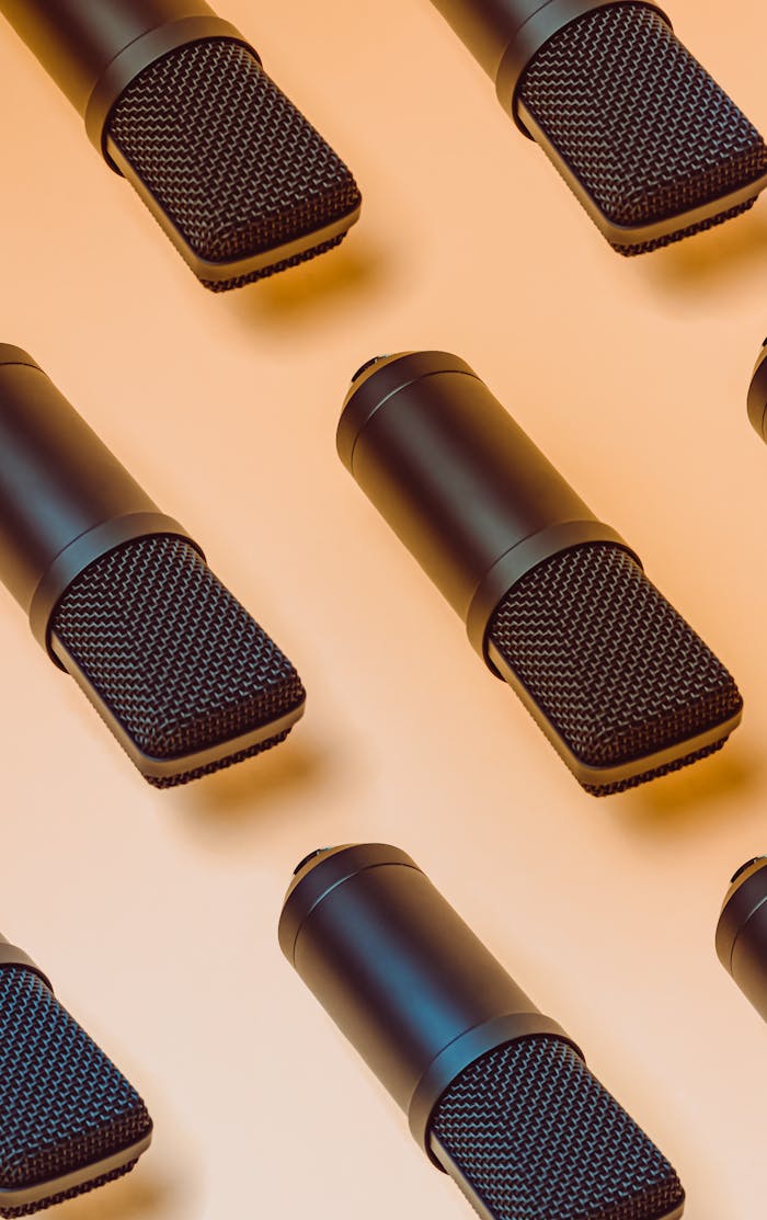 A modern arrangement of black microphones on a peach-toned background, perfect for audio themes.